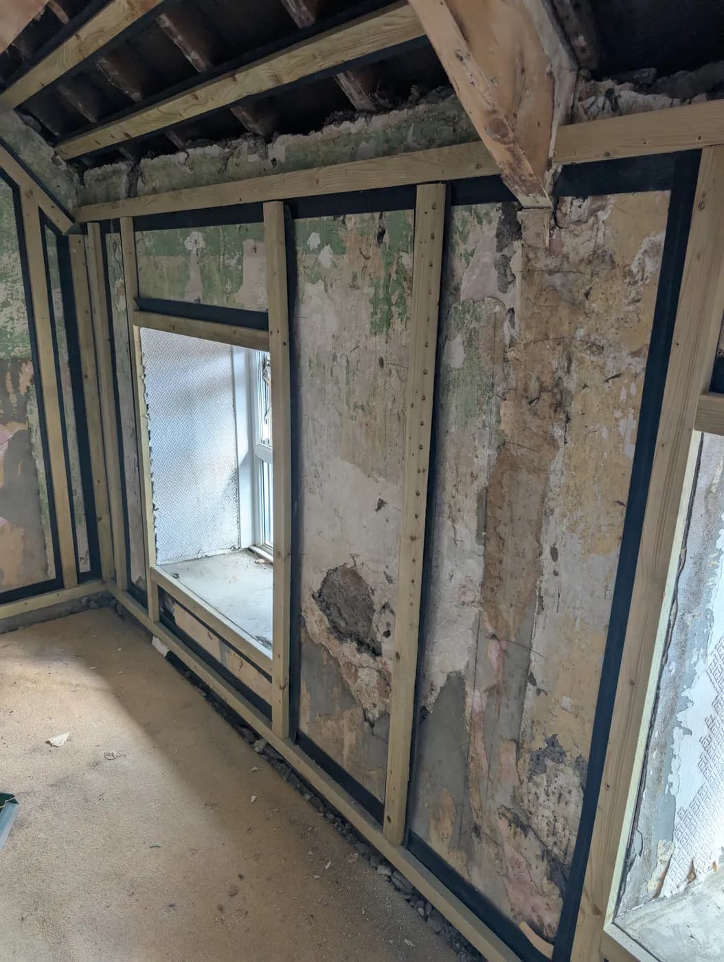 Insulation battens fixed to a solid wall inside a stripped room